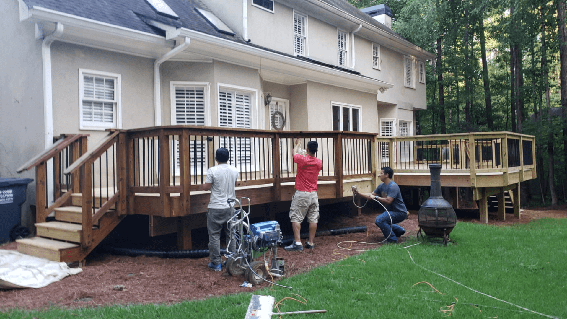 A modern balcony with a glass railing and outdoor seating overlooking a scenic view.