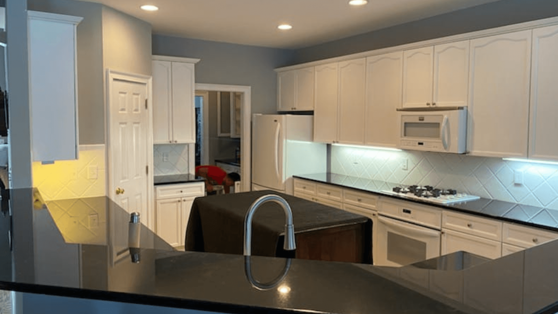 A modern kitchen with sleek countertops, stainless steel appliances, and open shelving.